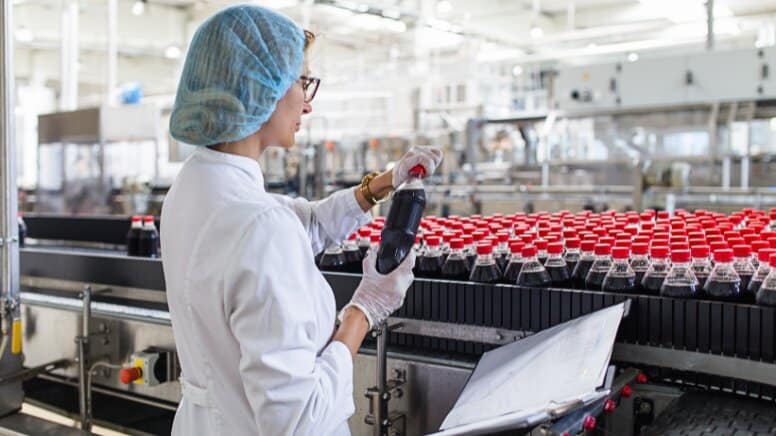 Une responsable qualité qui contrôle un soda d'une chaîne de production
