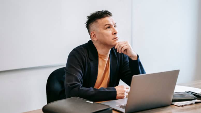 Un chef d'entreprise pensif qui se demande quels sont les piliers d'un système de management QSE