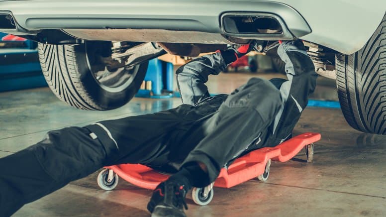 Un mécanicien réparant une voiture rappelée en concession