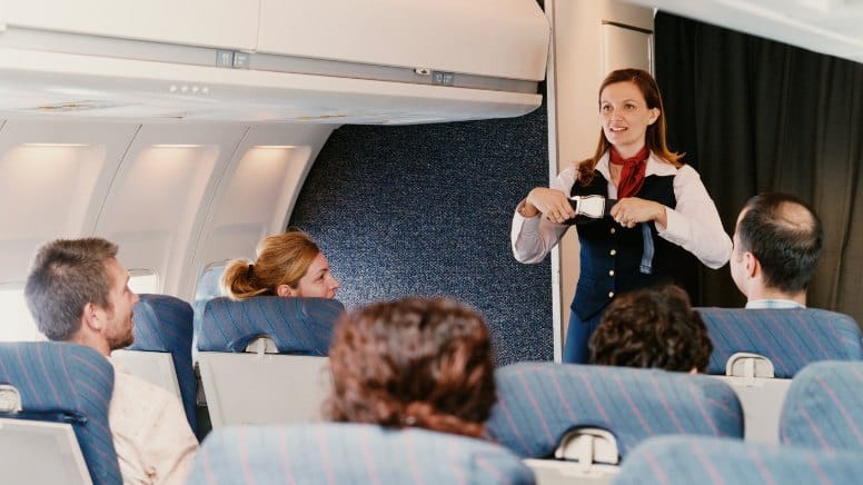 Une hotesse qui presente les informations de sécurité avant le décollage d'un avion