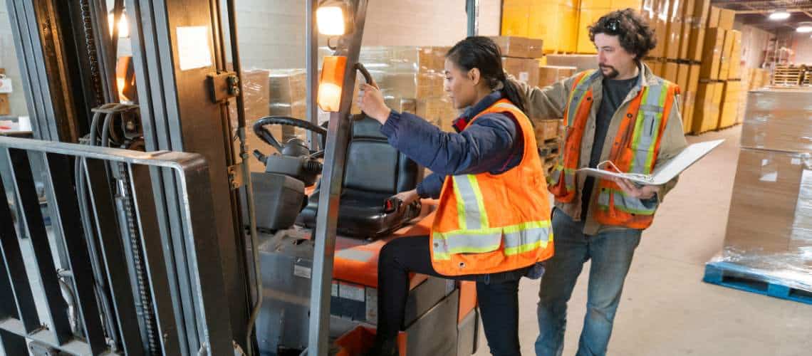 Un responsable ISO 45001 qui forme une ouvrière sur l'utilisation d'un chariot élévateur