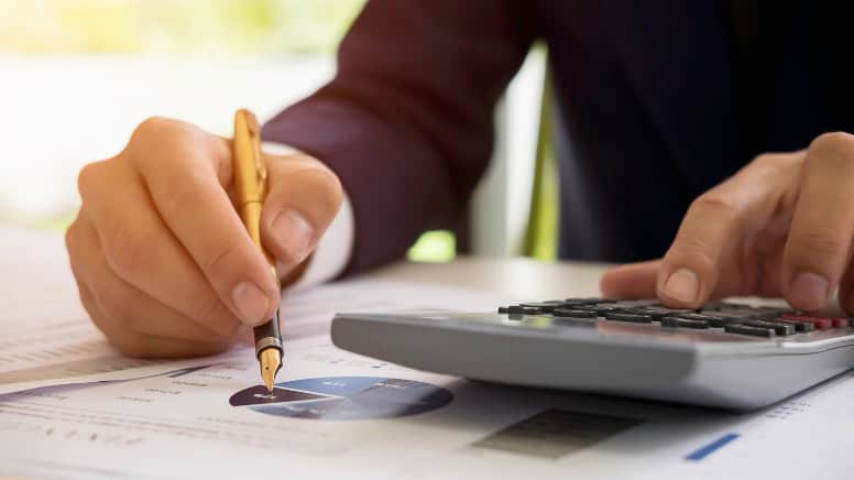 Une personne qui fait des calculs pour réduire les coûts de production de son entreprise